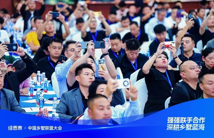 乡墅联盟大会现场参会嘉宾举手机拍摄